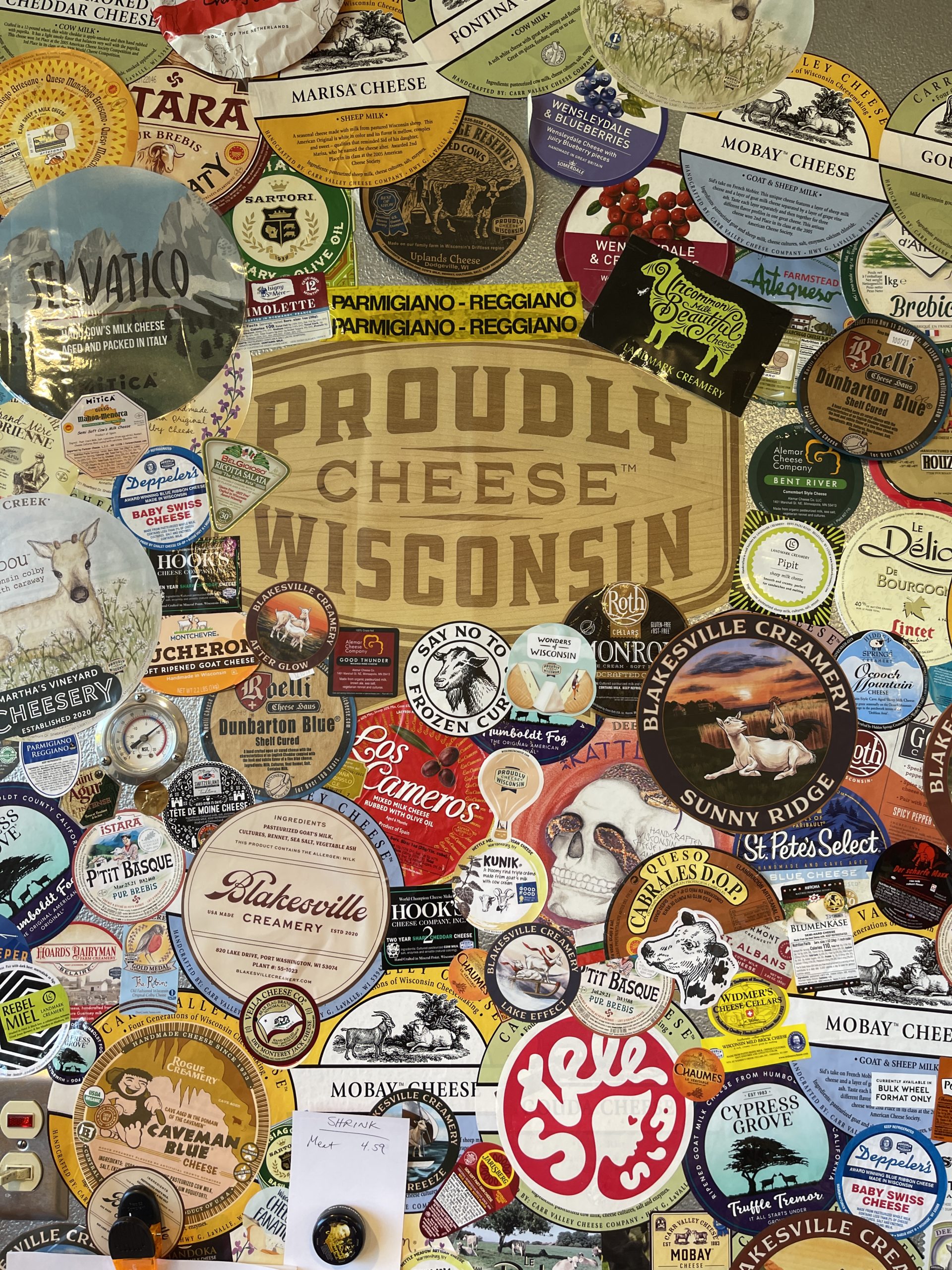"Proudly Wisconsin Cheese" sign surrounded by cheese stickers from makers and mongers