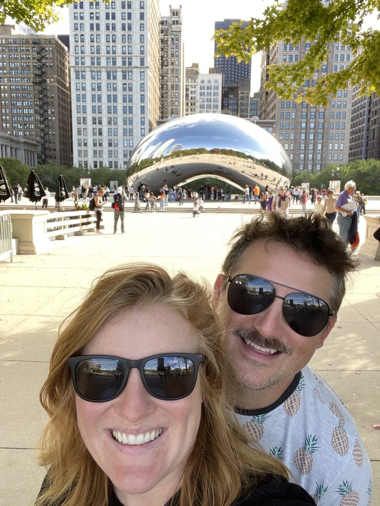 Morgen and Alex wearing sunglasses and smiling in from of the Chicago "Bean" sculpture