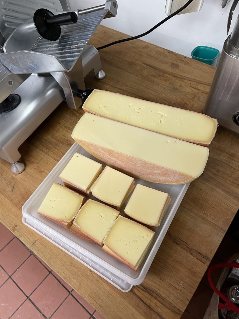 Prepped raclette cheese - slices for the grill pan and half-wheels for the raclette machine