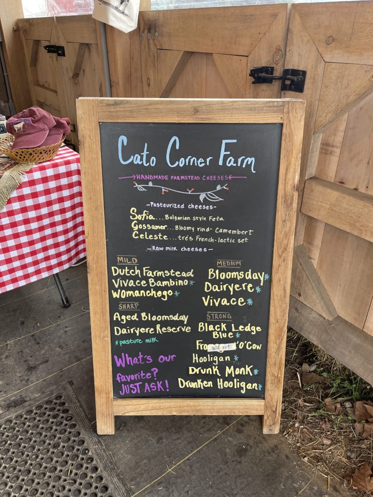 The chalkboard sign at the Cato Corner Farm Stand detailing what cheeses they have for sale that day.