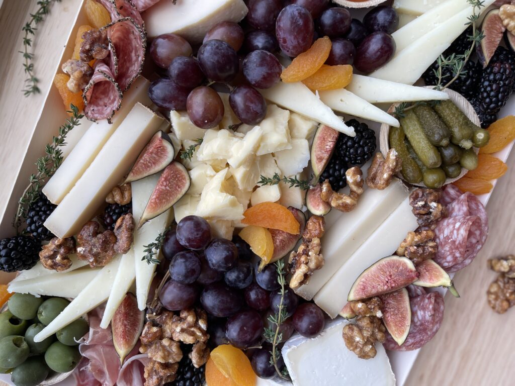 Up close shot of a large grazing box from Martha's Vineyard Cheesery! Beautifully arranged cheeses, charcuterie, fresh and dried fruits, pickles, olive, and nuts!