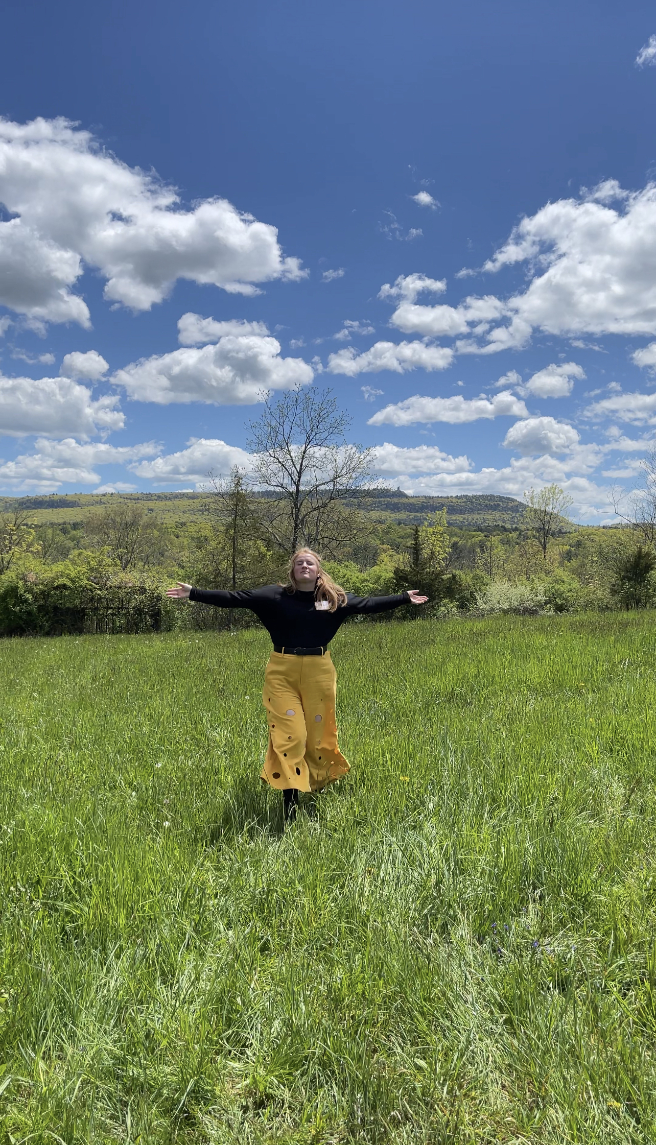 Morgen wearing her cheese pants and spinning in an open field, similar to the Sound of Music.